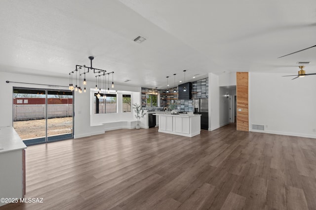 unfurnished living room featuring visible vents, a ceiling fan, wood finished floors, and vaulted ceiling