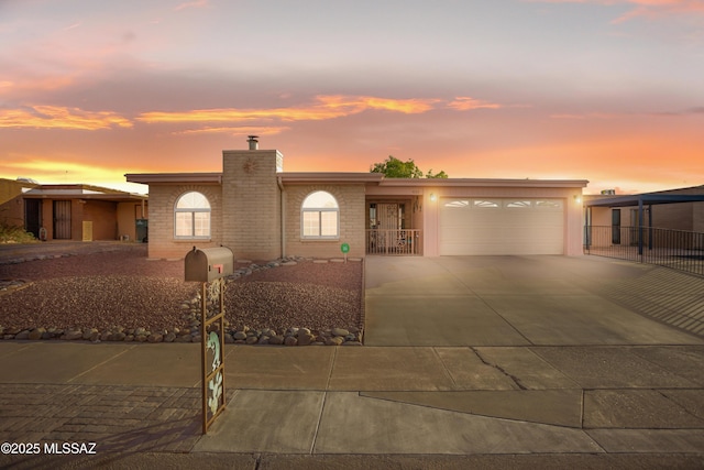 view of front of house with brick siding, driveway, a chimney, and a garage