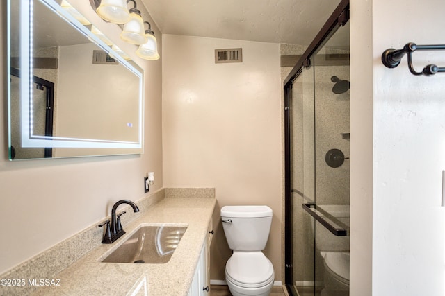 bathroom with visible vents, vanity, toilet, and a shower stall
