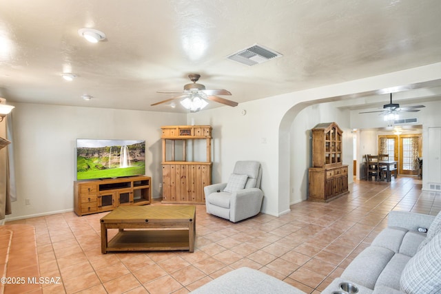 living room featuring a ceiling fan, arched walkways, visible vents, and light tile patterned flooring