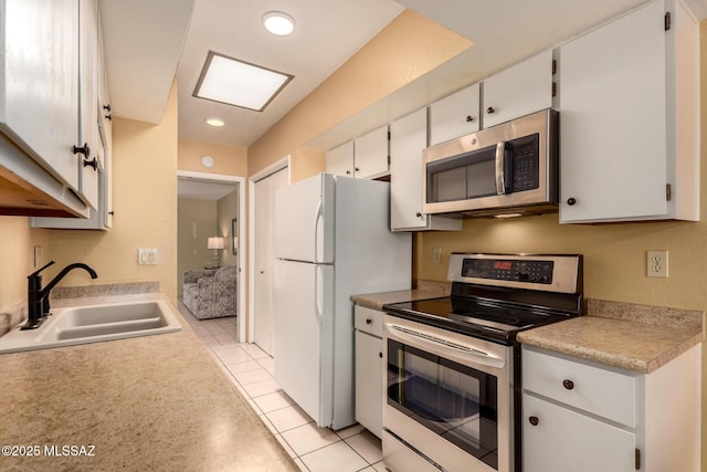kitchen with light tile patterned flooring, light countertops, white cabinetry, a sink, and appliances with stainless steel finishes