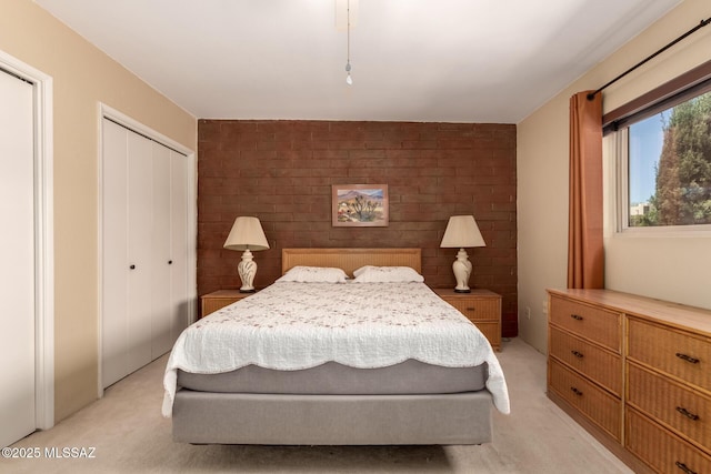 bedroom featuring light colored carpet and brick wall