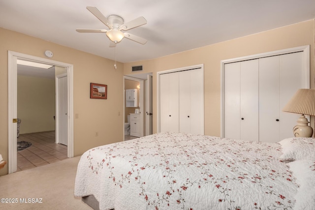 bedroom with ceiling fan, two closets, and visible vents