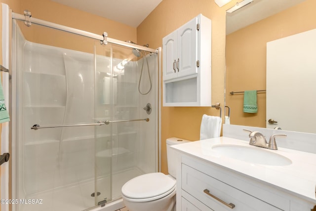 bathroom with vanity, a stall shower, and toilet