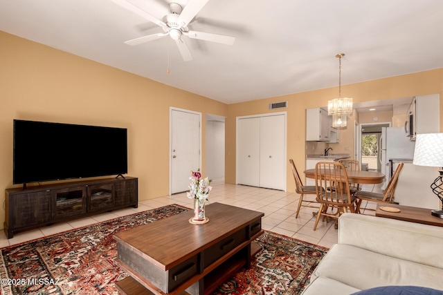 living room with visible vents, light tile patterned floors, and ceiling fan with notable chandelier