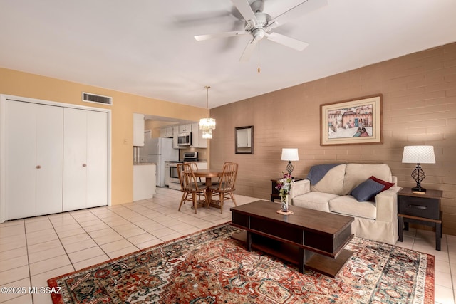 living area with light tile patterned floors, ceiling fan with notable chandelier, and visible vents