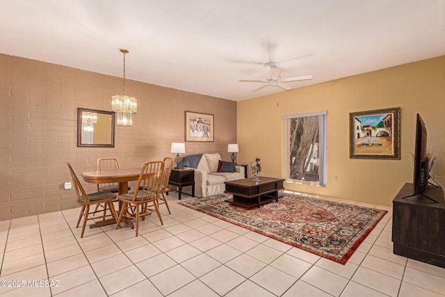 living room featuring light tile patterned flooring, brick wall, and ceiling fan with notable chandelier