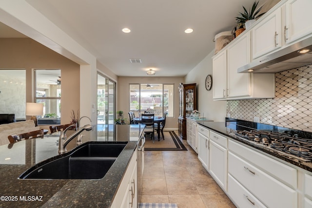 kitchen with gas cooktop, a sink, white cabinetry, decorative backsplash, and under cabinet range hood