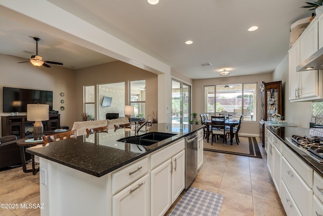kitchen featuring visible vents, open floor plan, dark stone counters, a sink, and stainless steel appliances