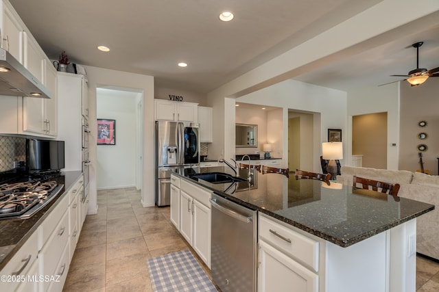 kitchen with decorative backsplash, a kitchen island with sink, appliances with stainless steel finishes, a sink, and open floor plan