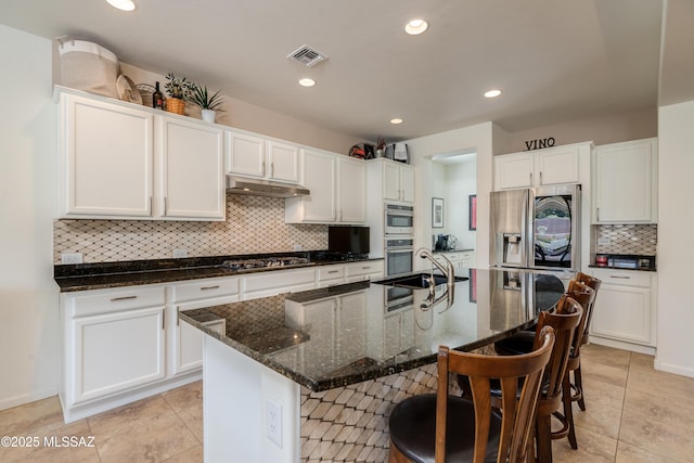 kitchen with a sink, stainless steel appliances, tasteful backsplash, under cabinet range hood, and visible vents