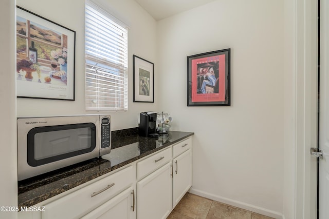 interior space featuring light tile patterned flooring, stainless steel microwave, and baseboards