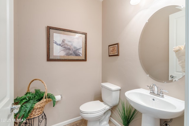 bathroom featuring baseboards, a sink, and toilet