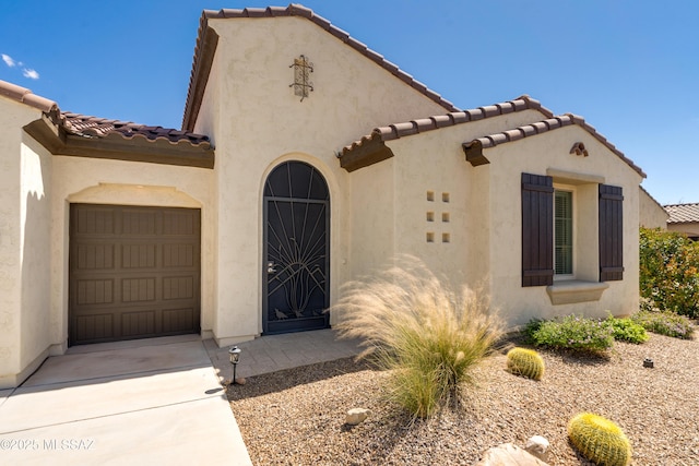 mediterranean / spanish home with a garage, driveway, a tile roof, and stucco siding