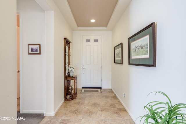 hallway featuring recessed lighting, baseboards, stone finish floor, and a tray ceiling