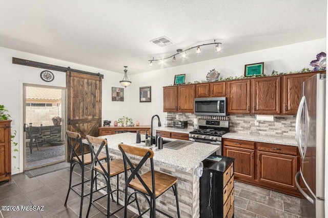 630 E Racine Pl, Casa Grande, AZ 85122 - kitchen with a barn door, a sink, stainless steel appliances, backsplash, and visible vents