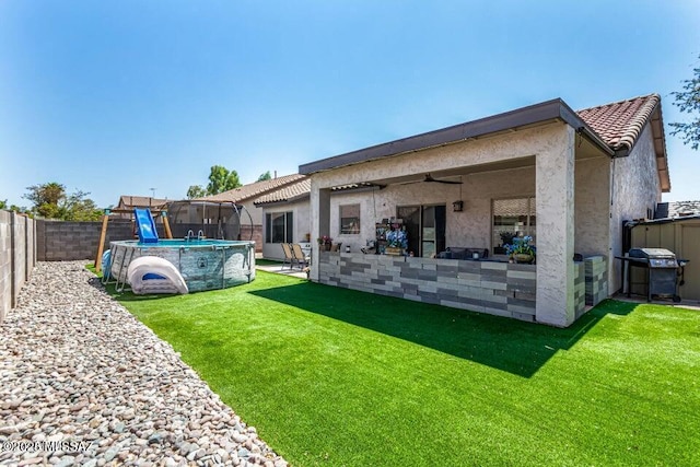 630 E Racine Pl, Casa Grande, AZ 85122 - back of house featuring a lawn, a ceiling fan, a fenced backyard, and stucco siding