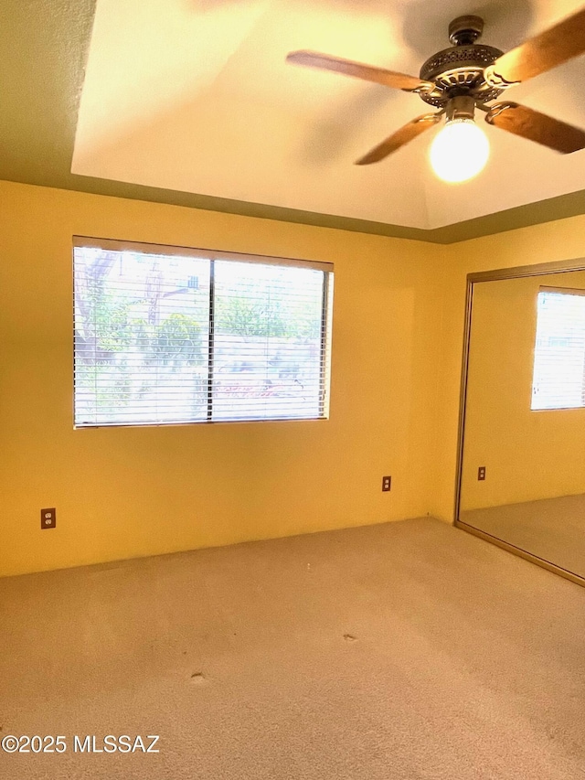 empty room featuring ceiling fan, plenty of natural light, and carpet