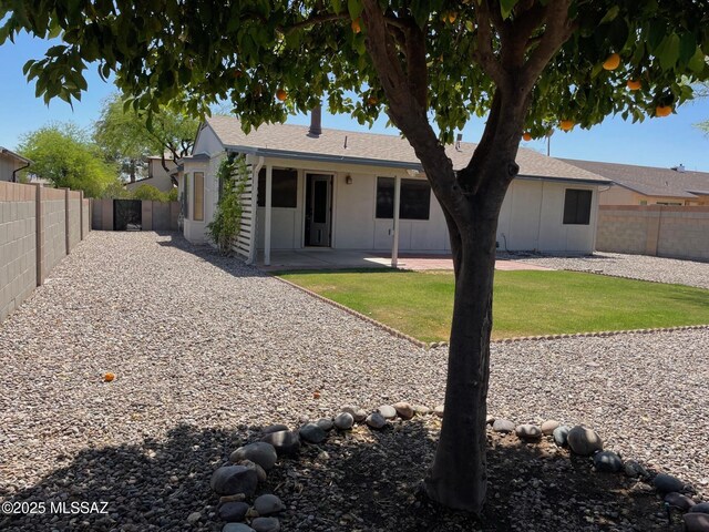rear view of property with a lawn, a fenced backyard, and a patio area