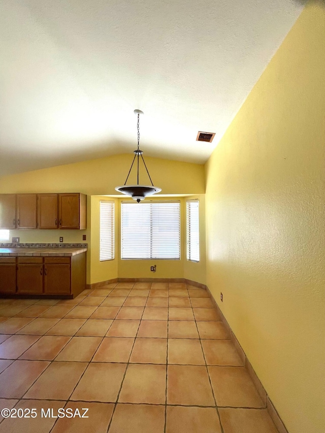 kitchen with visible vents, hanging light fixtures, light countertops, light tile patterned floors, and lofted ceiling