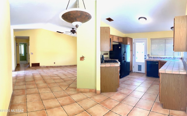 kitchen with tile countertops, lofted ceiling, a sink, and black appliances