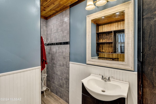 bathroom featuring vanity, wooden ceiling, wainscoting, and wood finished floors