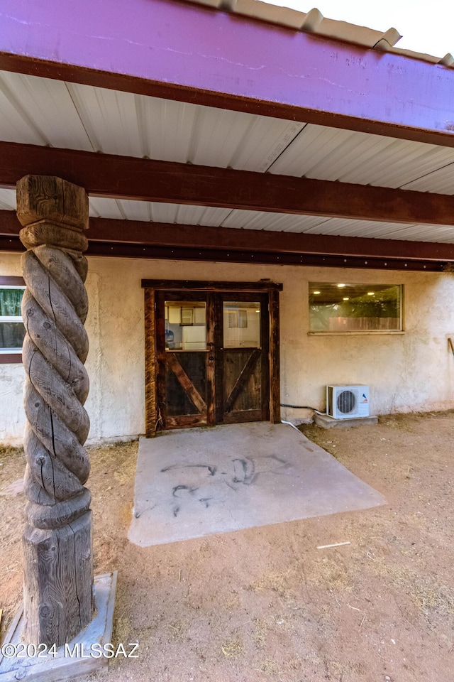 view of exterior entry with ac unit and stucco siding