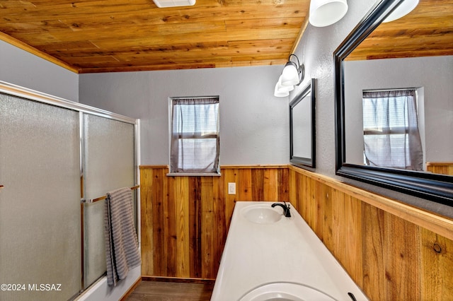 bathroom with wood ceiling, a shower stall, a sink, and a wainscoted wall