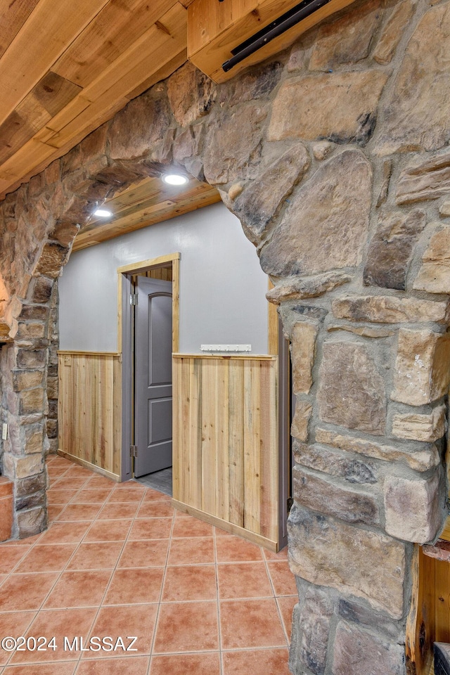 bonus room featuring light tile patterned flooring, wood walls, wood ceiling, and a wainscoted wall