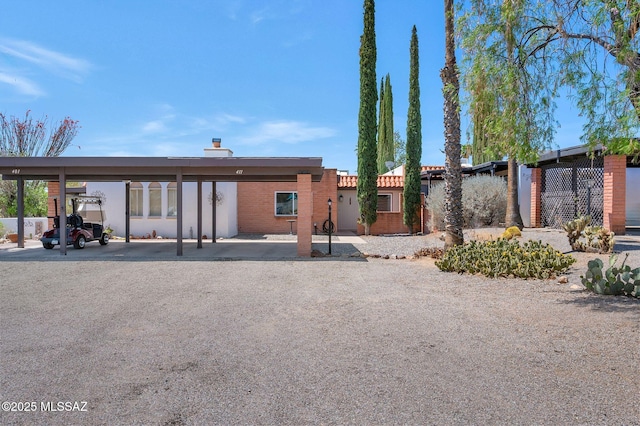 rear view of house featuring covered parking and stucco siding