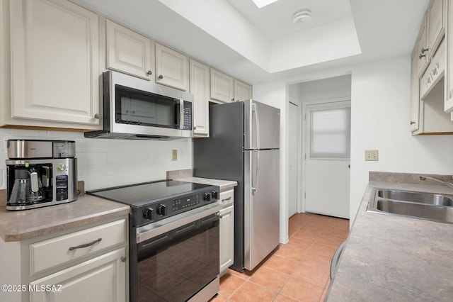 kitchen featuring decorative backsplash, light countertops, a sink, light tile patterned floors, and stainless steel appliances