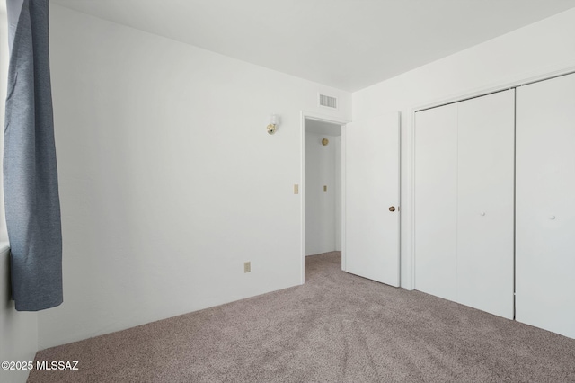 unfurnished bedroom with carpet, a closet, and visible vents