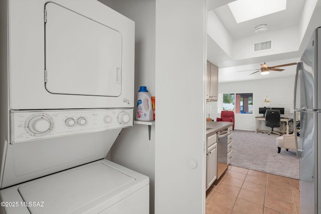 laundry room featuring laundry area, visible vents, stacked washer / drying machine, light carpet, and light tile patterned flooring