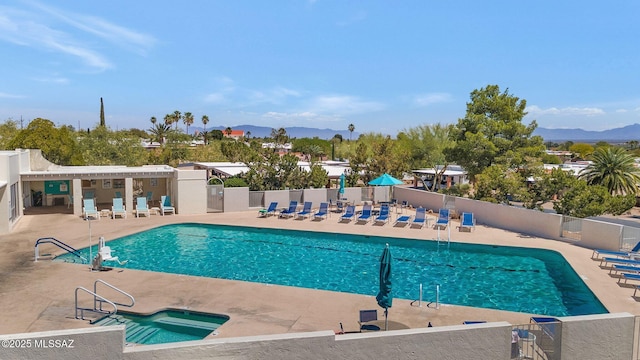 pool with a patio, fence, and a mountain view