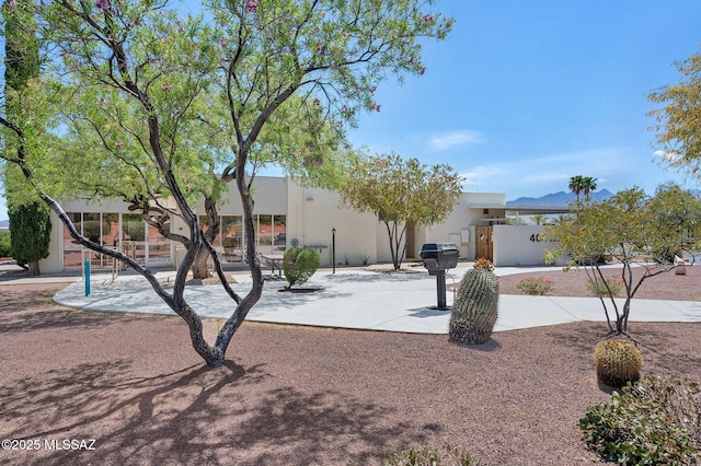 view of front of home featuring a mountain view, stucco siding, and fence