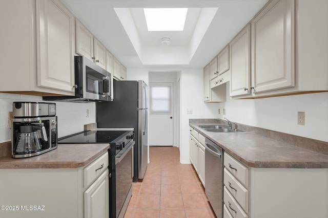 kitchen featuring tasteful backsplash, a sink, a raised ceiling, light tile patterned floors, and stainless steel appliances