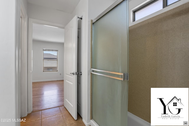 bathroom with a healthy amount of sunlight, tile patterned flooring, and a shower with door