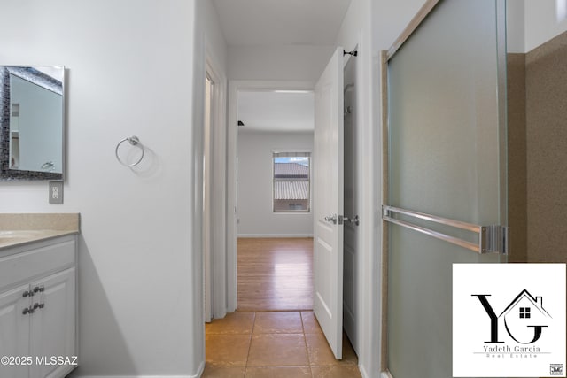 hall featuring baseboards and light tile patterned floors