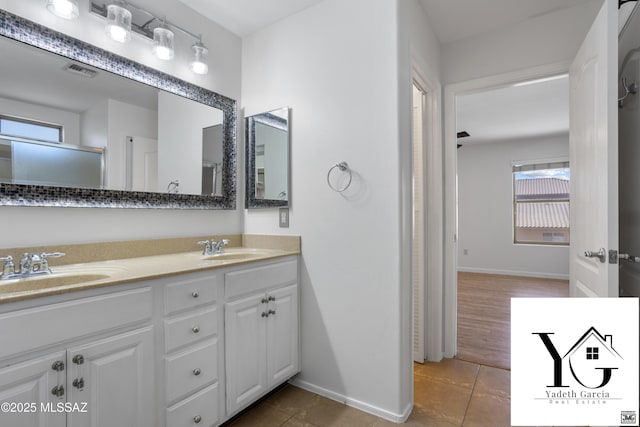 bathroom with double vanity, baseboards, visible vents, and a sink