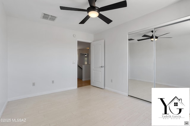 unfurnished bedroom with a ceiling fan, visible vents, wood finished floors, baseboards, and a closet