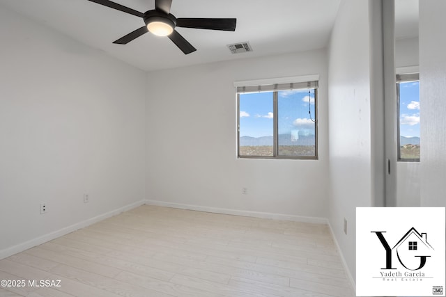 empty room with visible vents, a ceiling fan, baseboards, and wood finished floors