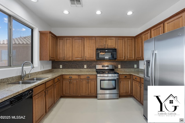 kitchen featuring visible vents, brown cabinetry, a sink, and black appliances