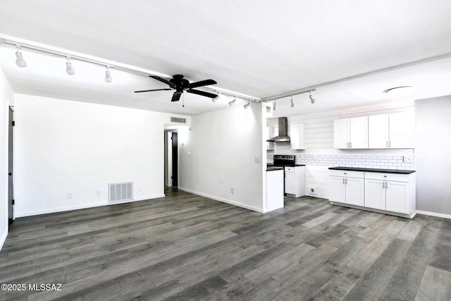 unfurnished living room featuring visible vents, rail lighting, dark wood finished floors, and ceiling fan