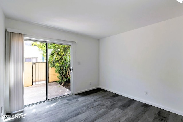 spare room featuring baseboards and dark wood-type flooring