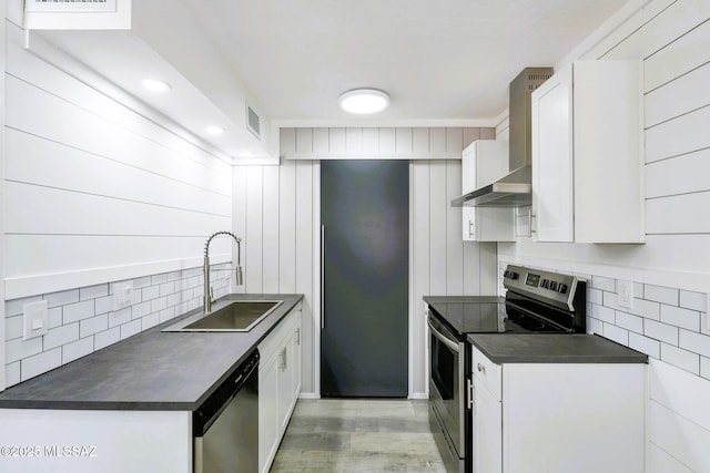 kitchen featuring decorative backsplash, appliances with stainless steel finishes, dark countertops, a sink, and wall chimney exhaust hood