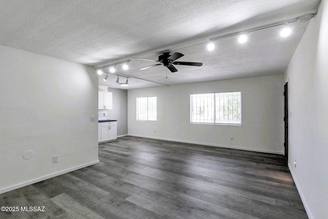 empty room with track lighting, a ceiling fan, a textured ceiling, and baseboards