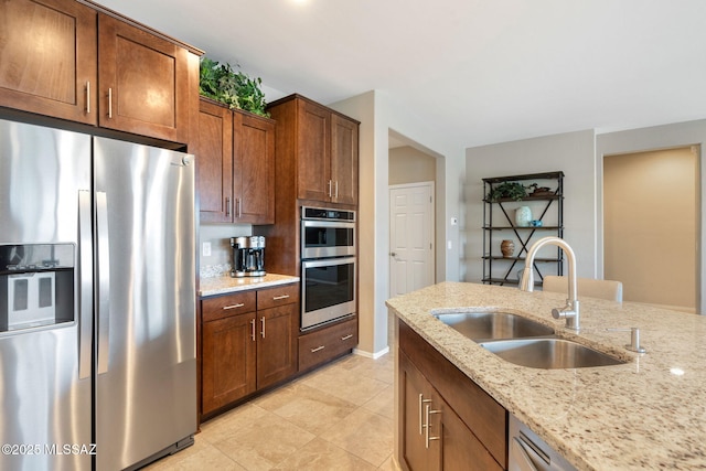 7084 W Cliff Spring Trl, Marana, AZ 85658 - kitchen with appliances with stainless steel finishes, a sink, light stone counters, light tile patterned floors, and brown cabinets
