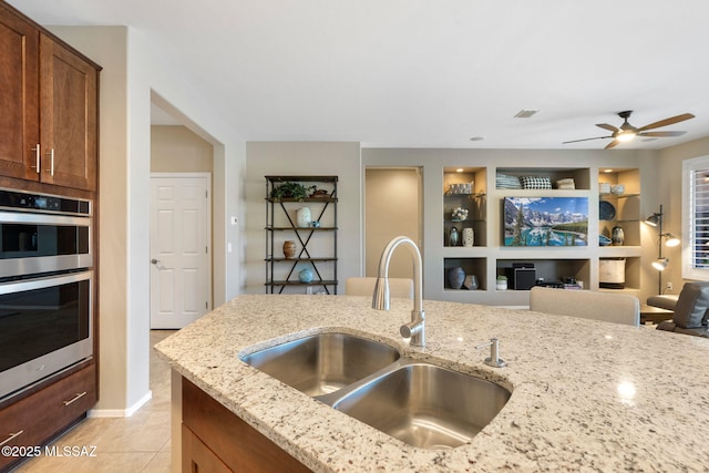 7084 W Cliff Spring Trl, Marana, AZ 85658 - kitchen with a sink, light stone countertops, double oven, and ceiling fan