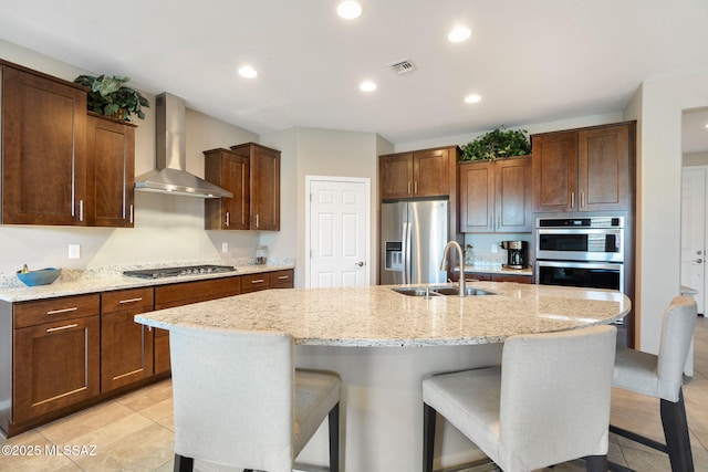 7084 W Cliff Spring Trl, Marana, AZ 85658 - kitchen with wall chimney exhaust hood, stainless steel appliances, a sink, a center island with sink, and a breakfast bar