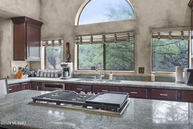 kitchen featuring stainless steel gas stovetop, stone counters, a sink, and dishwasher